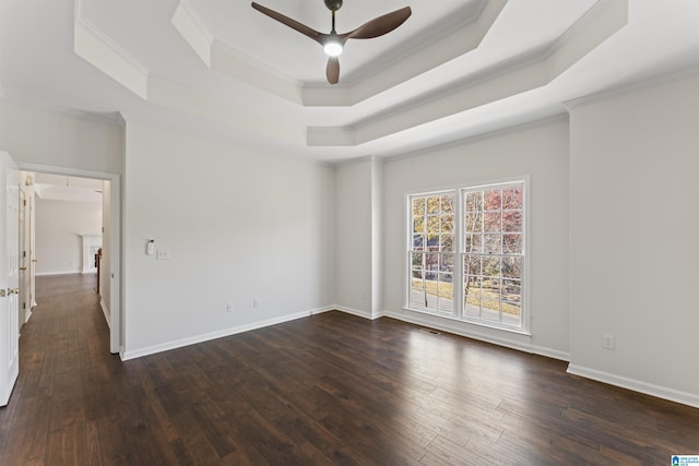 empty room featuring a raised ceiling, crown molding, and dark hardwood / wood-style floors