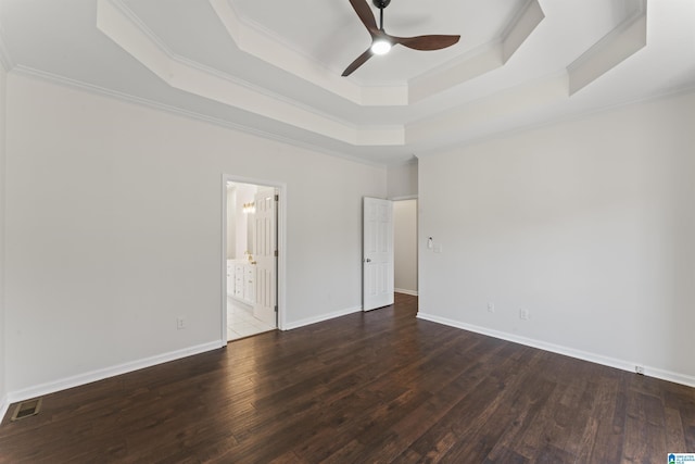 interior space with a tray ceiling, ceiling fan, dark hardwood / wood-style flooring, and ornamental molding