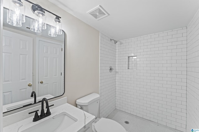 bathroom featuring tiled shower, vanity, and toilet