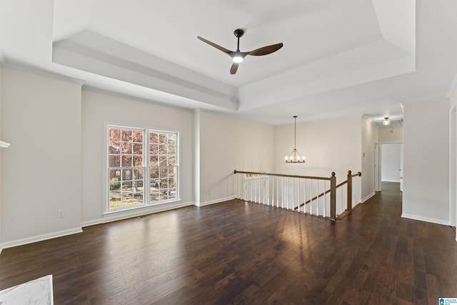 spare room featuring a tray ceiling, dark hardwood / wood-style flooring, and ceiling fan with notable chandelier