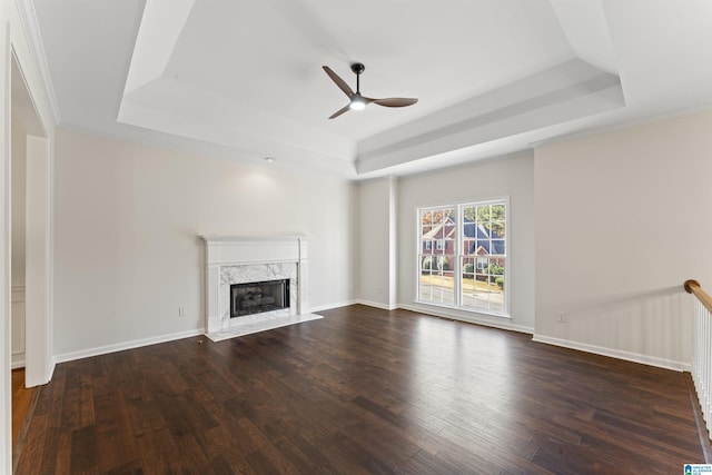 unfurnished living room with ceiling fan, a raised ceiling, and dark wood-type flooring