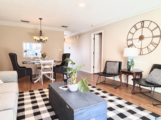 living room featuring ornamental molding, a textured ceiling, hardwood / wood-style flooring, and a notable chandelier