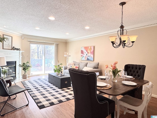 dining area featuring a textured ceiling, hardwood / wood-style flooring, crown molding, and a notable chandelier