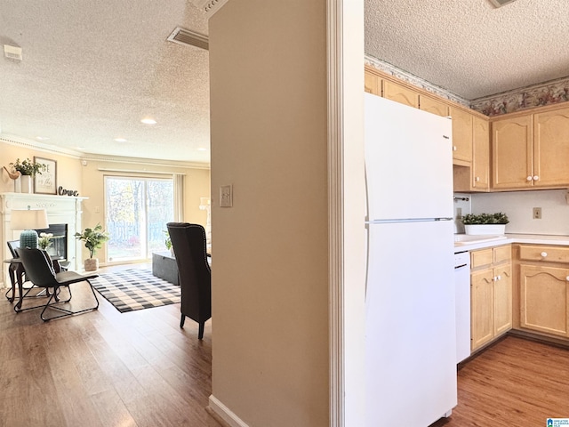 kitchen with light brown cabinets, light wood-type flooring, white appliances, and crown molding