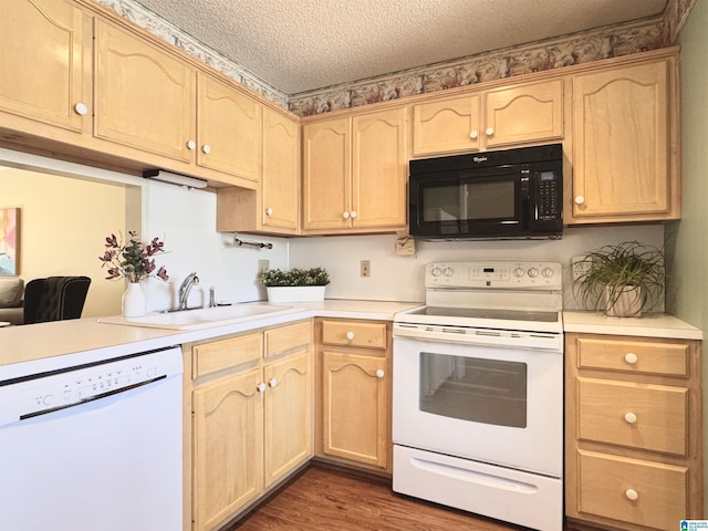 kitchen with light brown cabinetry, white appliances, and sink