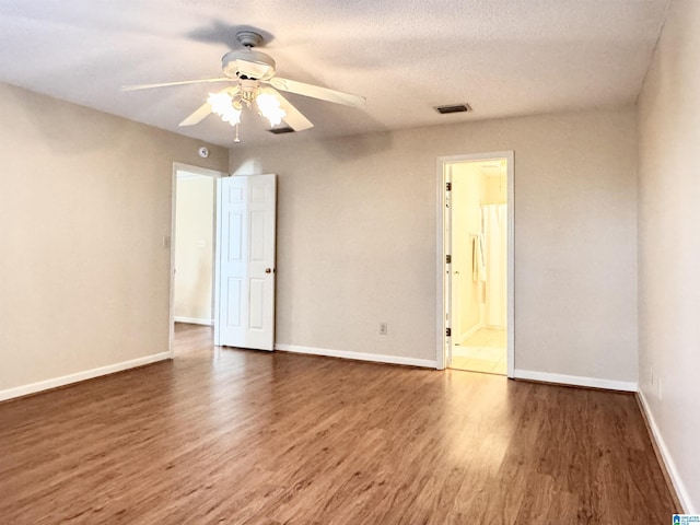 spare room featuring ceiling fan, dark wood-type flooring, and a textured ceiling