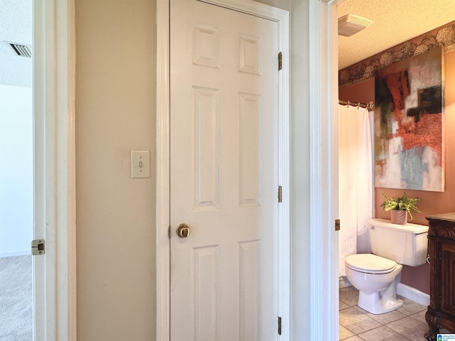 bathroom with tile patterned flooring, vanity, a textured ceiling, and toilet