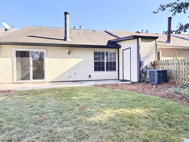 rear view of house featuring central air condition unit and a yard