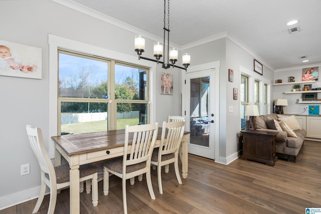 dining room with crown molding, dark wood-type flooring, and an inviting chandelier