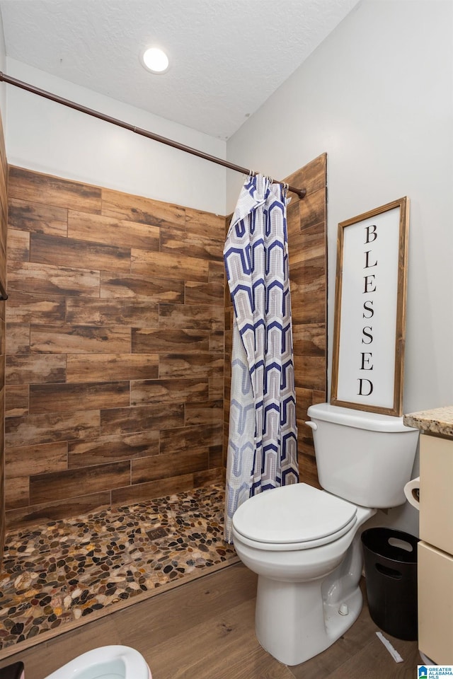 bathroom featuring toilet, wood-type flooring, a textured ceiling, and walk in shower