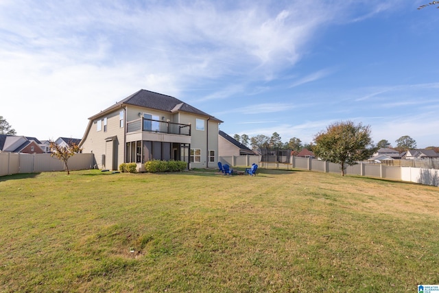 rear view of house featuring a trampoline, a balcony, and a lawn