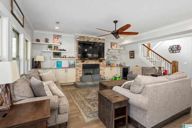 living room with ornamental molding, beverage cooler, ceiling fan, wood-type flooring, and a fireplace