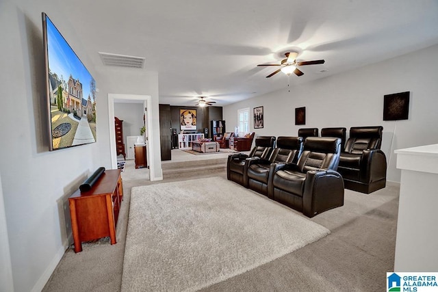 cinema room with ceiling fan and light colored carpet