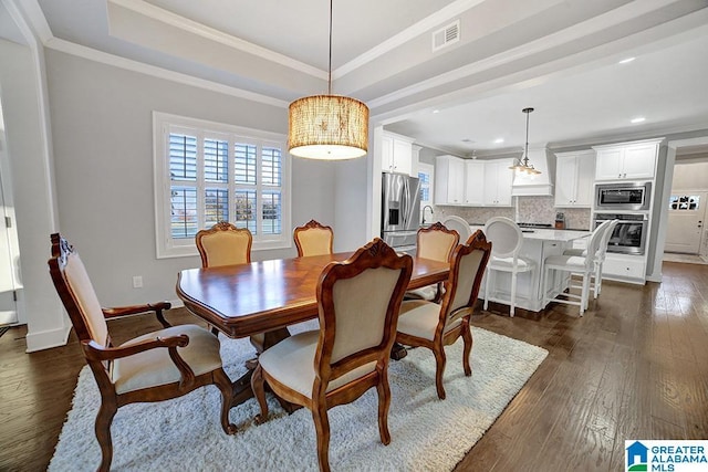 dining room featuring crown molding, a raised ceiling, and dark wood-type flooring