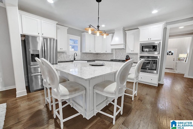 kitchen featuring pendant lighting, a center island, premium range hood, white cabinetry, and stainless steel appliances