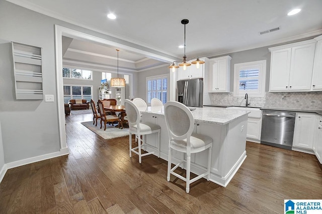 kitchen with stainless steel appliances, white cabinetry, a wealth of natural light, and dark hardwood / wood-style floors