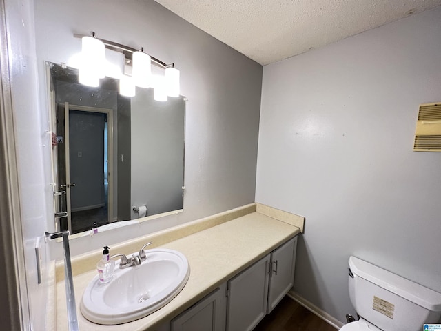 bathroom featuring vanity, a textured ceiling, and toilet