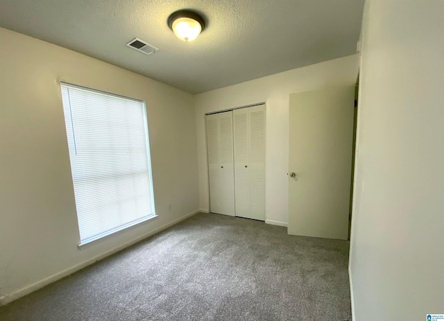 unfurnished bedroom featuring a textured ceiling, light colored carpet, and a closet