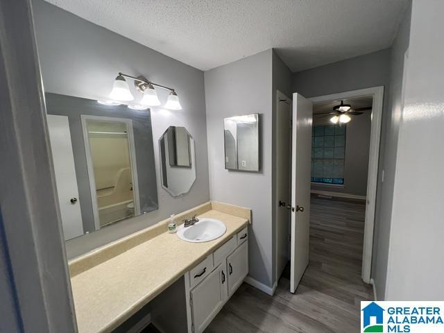 bathroom featuring hardwood / wood-style flooring, vanity, ceiling fan, and a textured ceiling