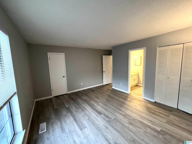 unfurnished bedroom featuring light wood-type flooring, a closet, and connected bathroom