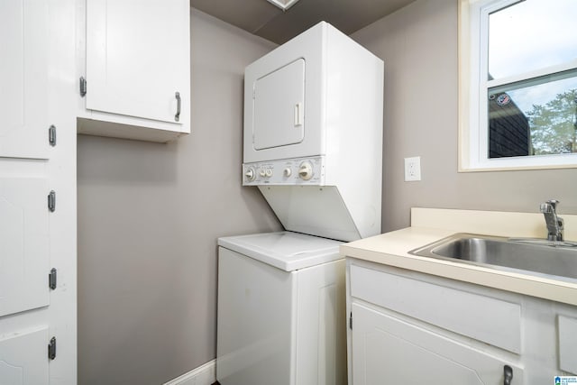 washroom featuring cabinets, stacked washing maching and dryer, and sink