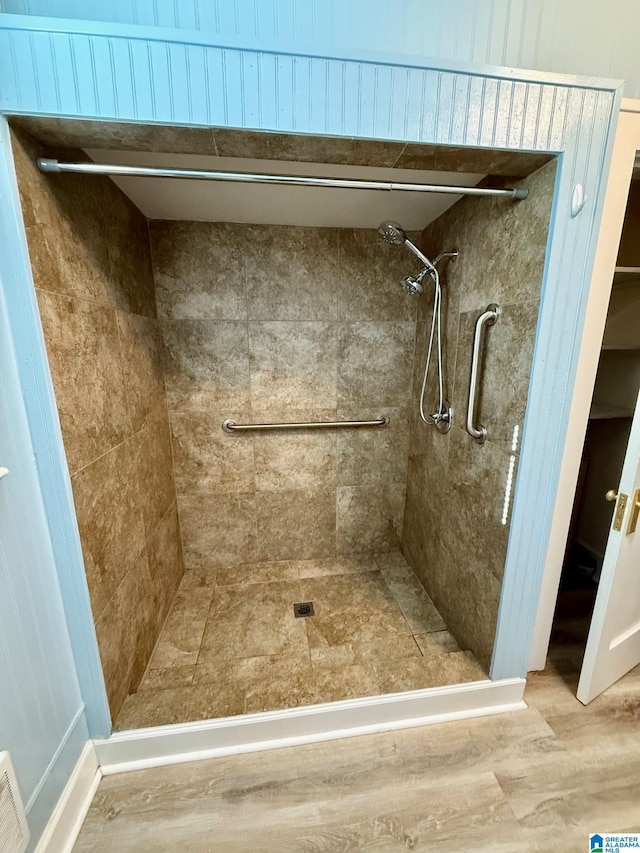 bathroom with hardwood / wood-style flooring and tiled shower