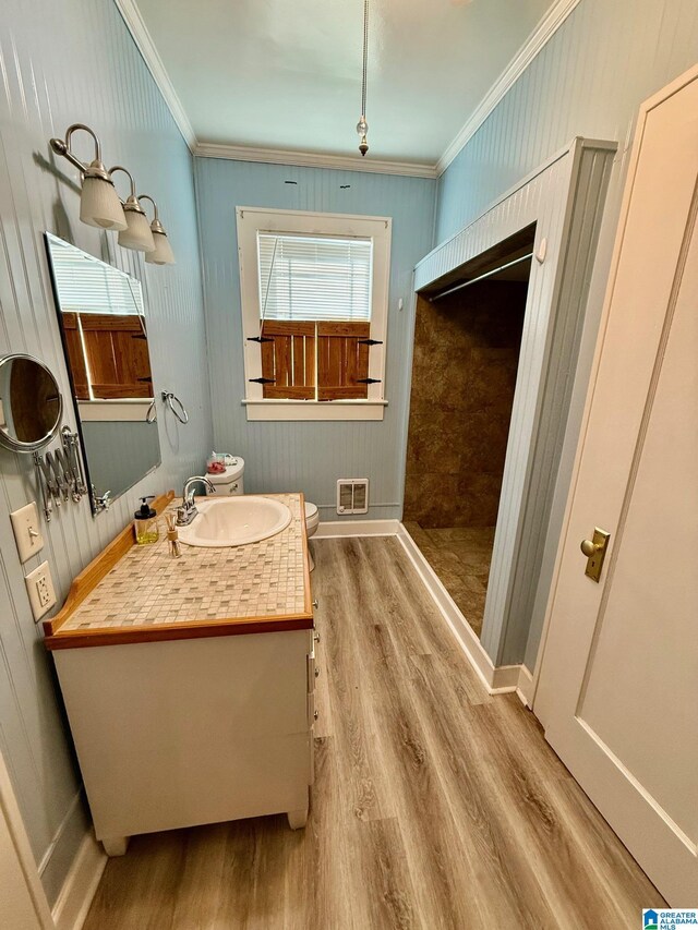 bathroom with crown molding, vanity, wood-type flooring, and toilet