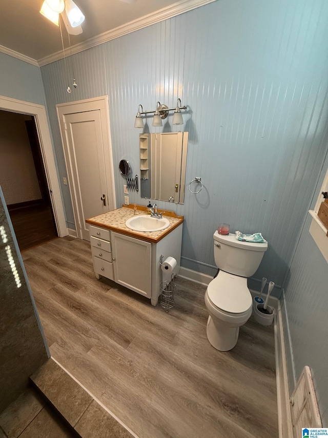 bathroom with ornamental molding, vanity, ceiling fan, wood-type flooring, and toilet