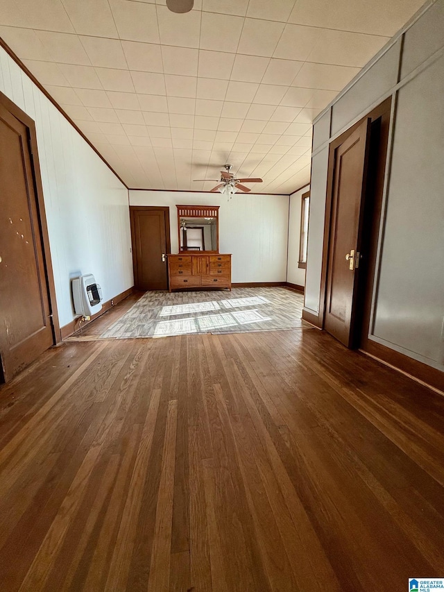 unfurnished living room featuring wood-type flooring, heating unit, and ceiling fan