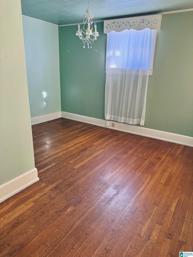 spare room with crown molding, a chandelier, and hardwood / wood-style flooring