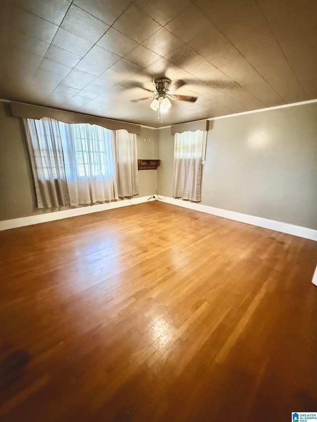 spare room with hardwood / wood-style floors, ceiling fan, crown molding, and a wealth of natural light