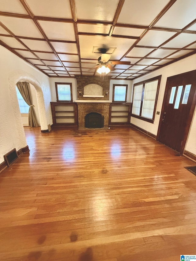 unfurnished living room featuring light hardwood / wood-style floors, a brick fireplace, ceiling fan, and coffered ceiling