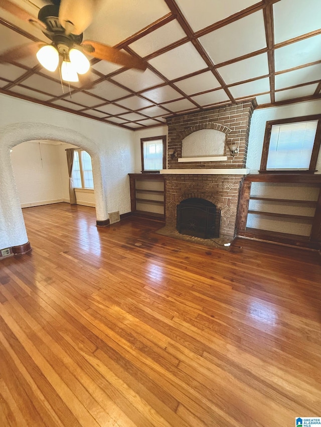 unfurnished living room featuring ceiling fan, wood-type flooring, a fireplace, and coffered ceiling