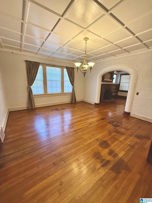 unfurnished living room featuring wood-type flooring, an inviting chandelier, and coffered ceiling