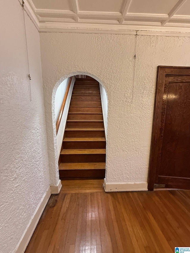 staircase featuring wood-type flooring and coffered ceiling