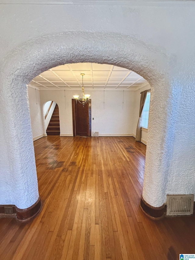 unfurnished room featuring hardwood / wood-style flooring, coffered ceiling, and an inviting chandelier