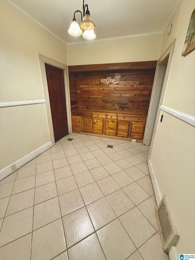 unfurnished dining area with a notable chandelier, light tile patterned floors, and ornamental molding