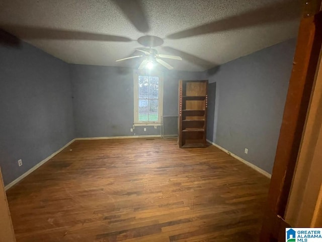 unfurnished bedroom with a textured ceiling, dark hardwood / wood-style flooring, vaulted ceiling, and ceiling fan