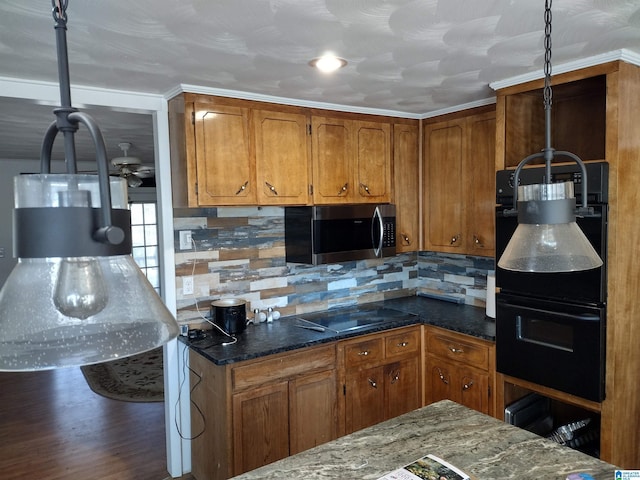 kitchen with pendant lighting, black appliances, crown molding, dark hardwood / wood-style floors, and dark stone countertops