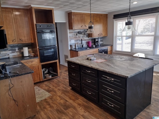 kitchen featuring pendant lighting, a center island, dark stone counters, black appliances, and dark hardwood / wood-style floors