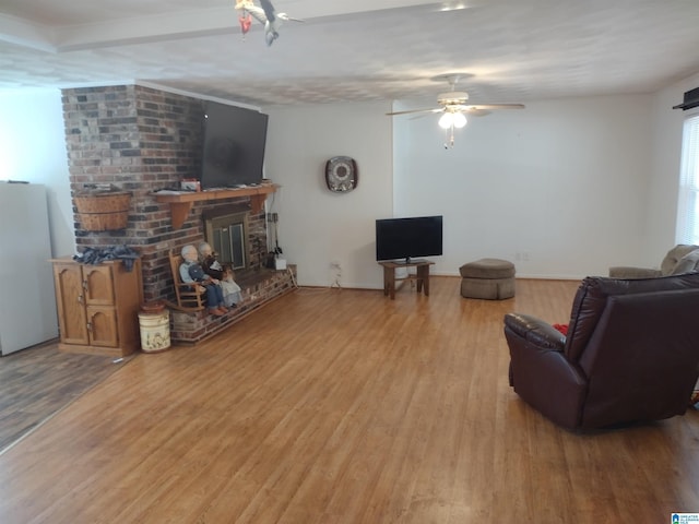 living room featuring a brick fireplace, ceiling fan, and light hardwood / wood-style flooring