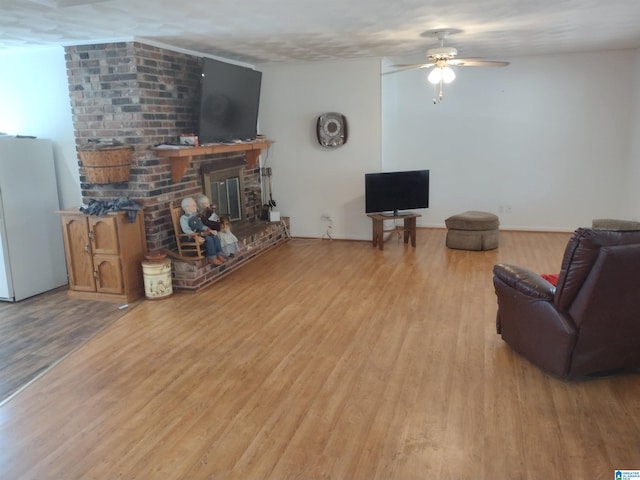 living room featuring a brick fireplace, light hardwood / wood-style flooring, and ceiling fan