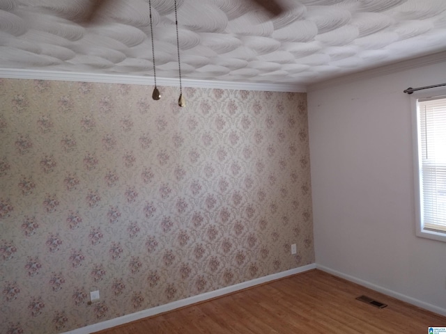 spare room featuring wood-type flooring and crown molding