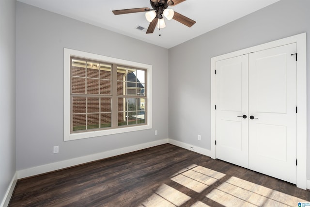 unfurnished bedroom with dark hardwood / wood-style flooring, a closet, and ceiling fan