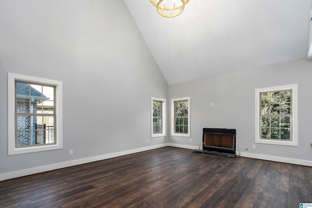 unfurnished living room featuring dark hardwood / wood-style floors, high vaulted ceiling, plenty of natural light, and a notable chandelier