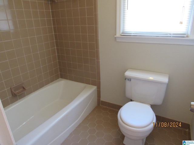 bathroom featuring tile patterned floors, tiled shower / bath combo, and toilet