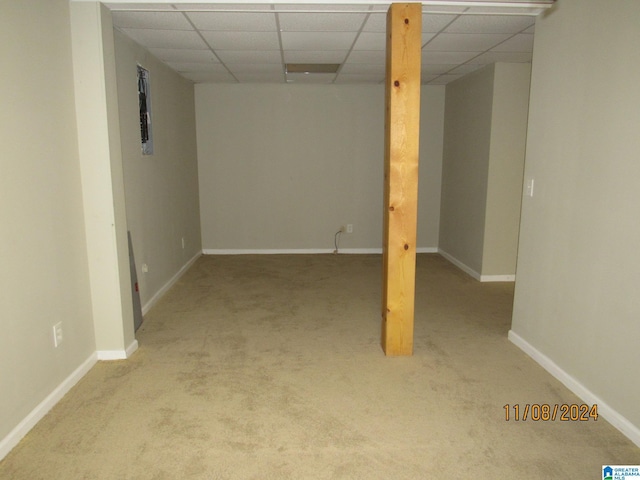 basement featuring a paneled ceiling and light colored carpet