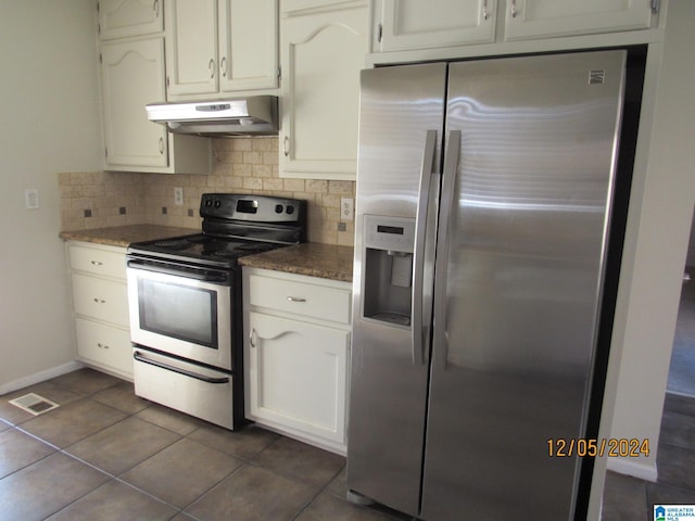 kitchen with tasteful backsplash, ventilation hood, stainless steel appliances, dark tile patterned floors, and white cabinetry