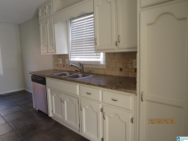 kitchen with backsplash, white cabinets, sink, stainless steel dishwasher, and dark tile patterned floors