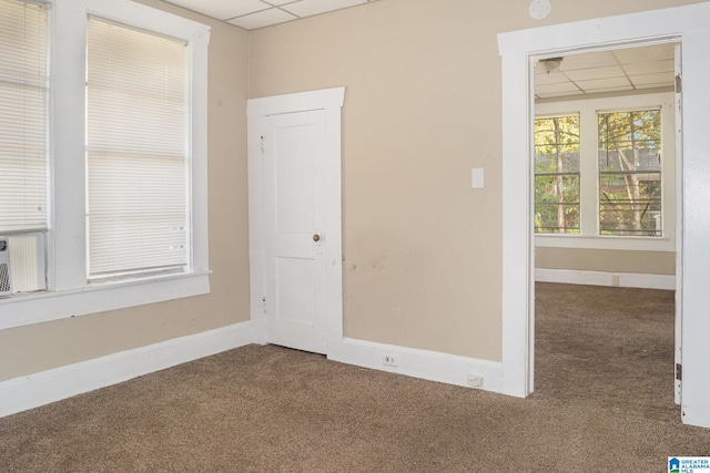 carpeted empty room featuring a drop ceiling